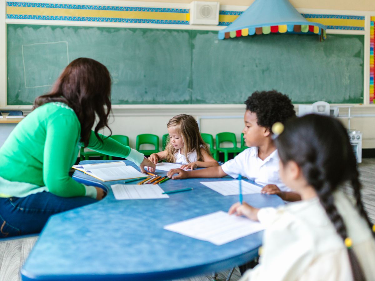 Children learning at a classroom table with a teacher